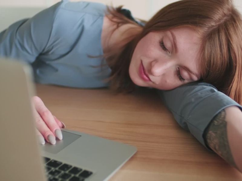 Devojka leži na stolu ispred laptopa